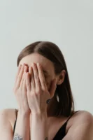 A woman covers her face - Credits: pexels