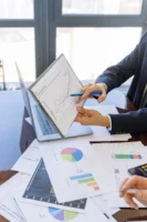 Business professionals discussing financial graphs - Credits: pexels