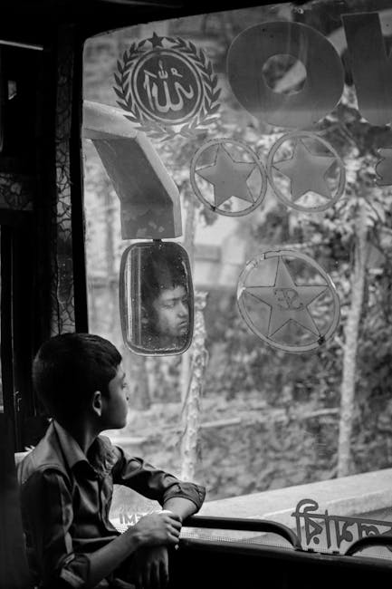 A young boy gazes out of a bus window in Ulipur, Bangladesh, captured in black and white. - Credits: pexels