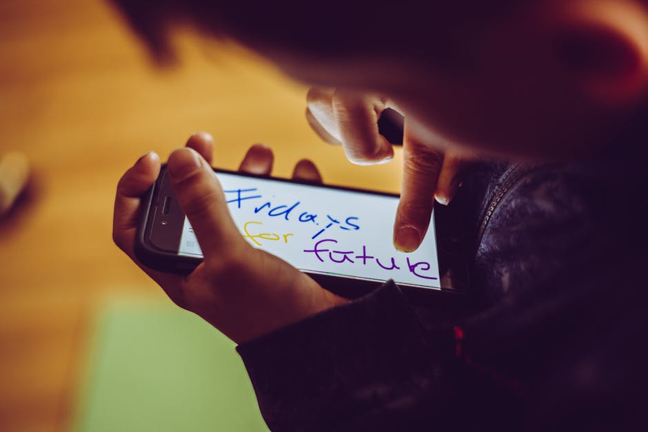 A close-up of a child using a smartphone, highlighting a 'Fridays for Future' message, symbolizing youthful involvement in climate activism. - Credits: pexels