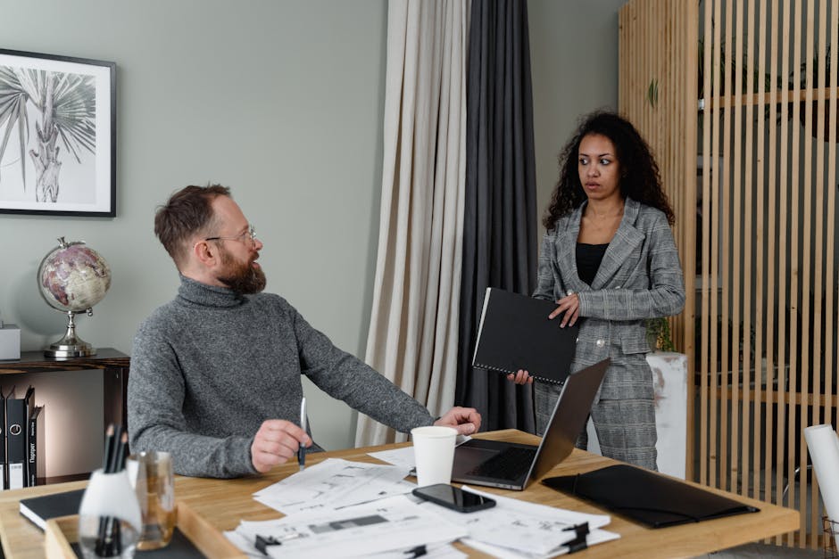 Two colleagues engaged in discussion with documents in a modern office setting. - Credits: pexels